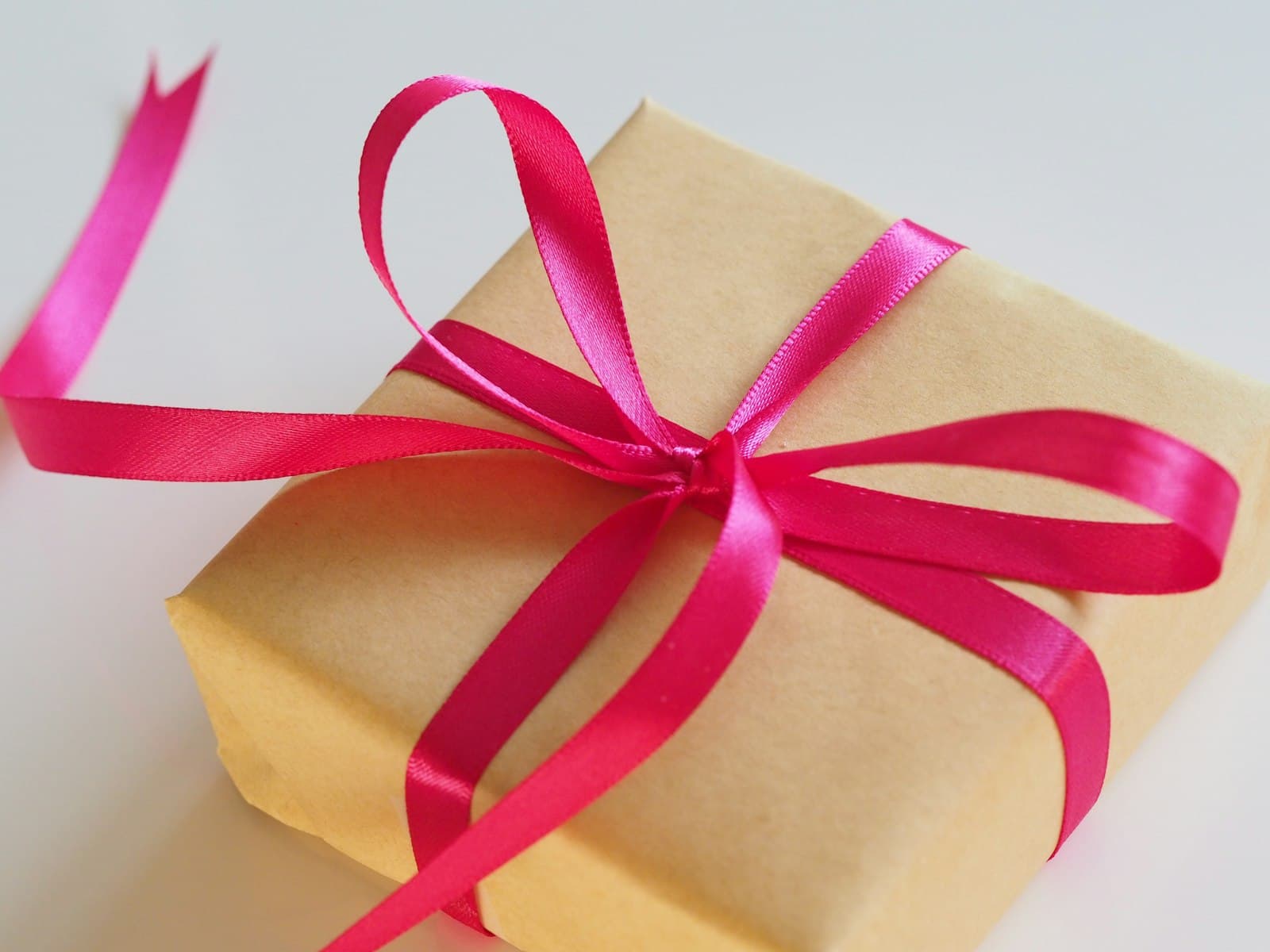 A gift wrapped in kraft paper with a magenta ribbon